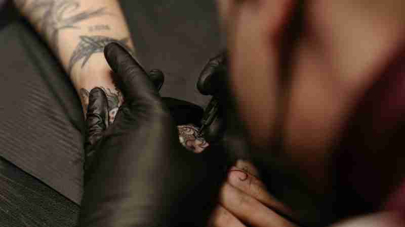 Tattoo artist working on a detailed freehand design on a client's arm., tags: van - pexel