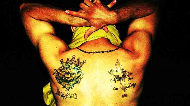 Latin King gang member showing his gang tattoo, a lion with a crown, and signifying the 5 point star with his hands, tags: voormalige bendeleden en van gratis - CC BY-SA