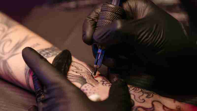 Close-up of a tattoo artist applying ink on a client's arm with precision., tags: madi familie met persoonlijke - pexel